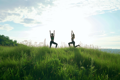 Image of girls doing yoga on a grassy hill fostering