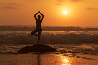 Silhouette photo of girl doing yoga in sunrise on beach